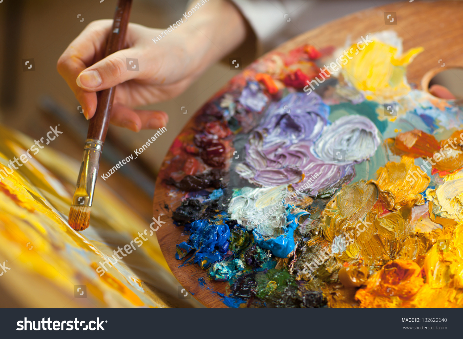 artist paints a picture of oil paint brush in hand with palette closeup #132622640