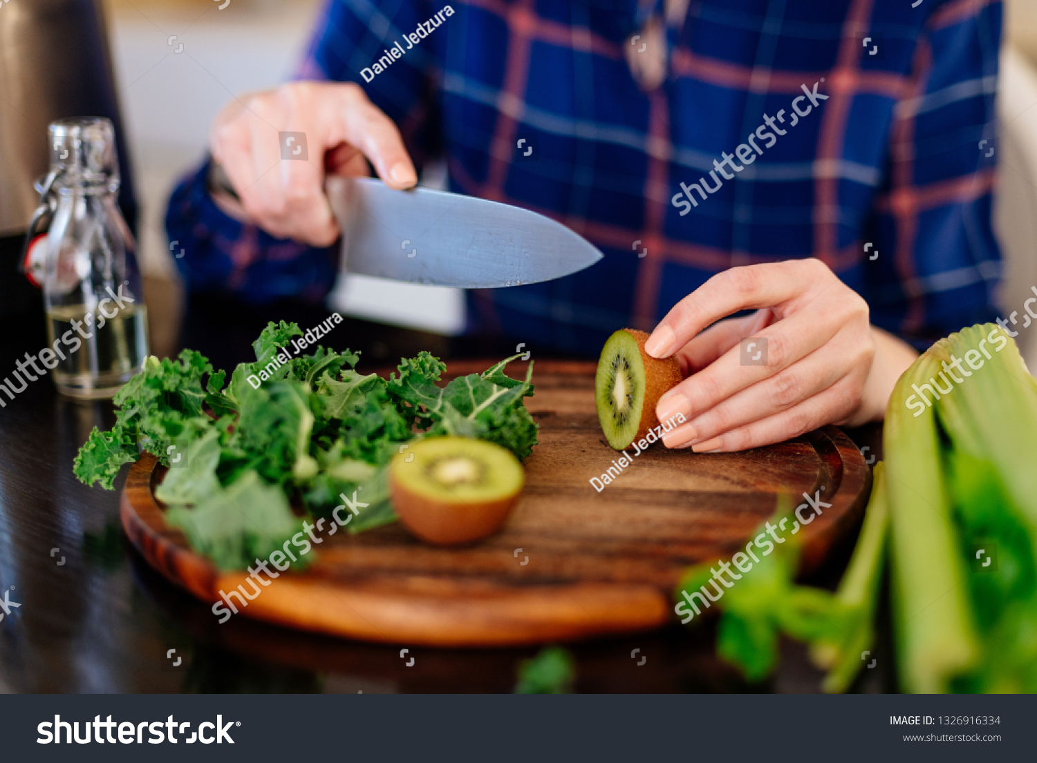 Woman cutting kiwi fruit in kitchen. Female preparing smoothie. Fresh organic food #1326916334