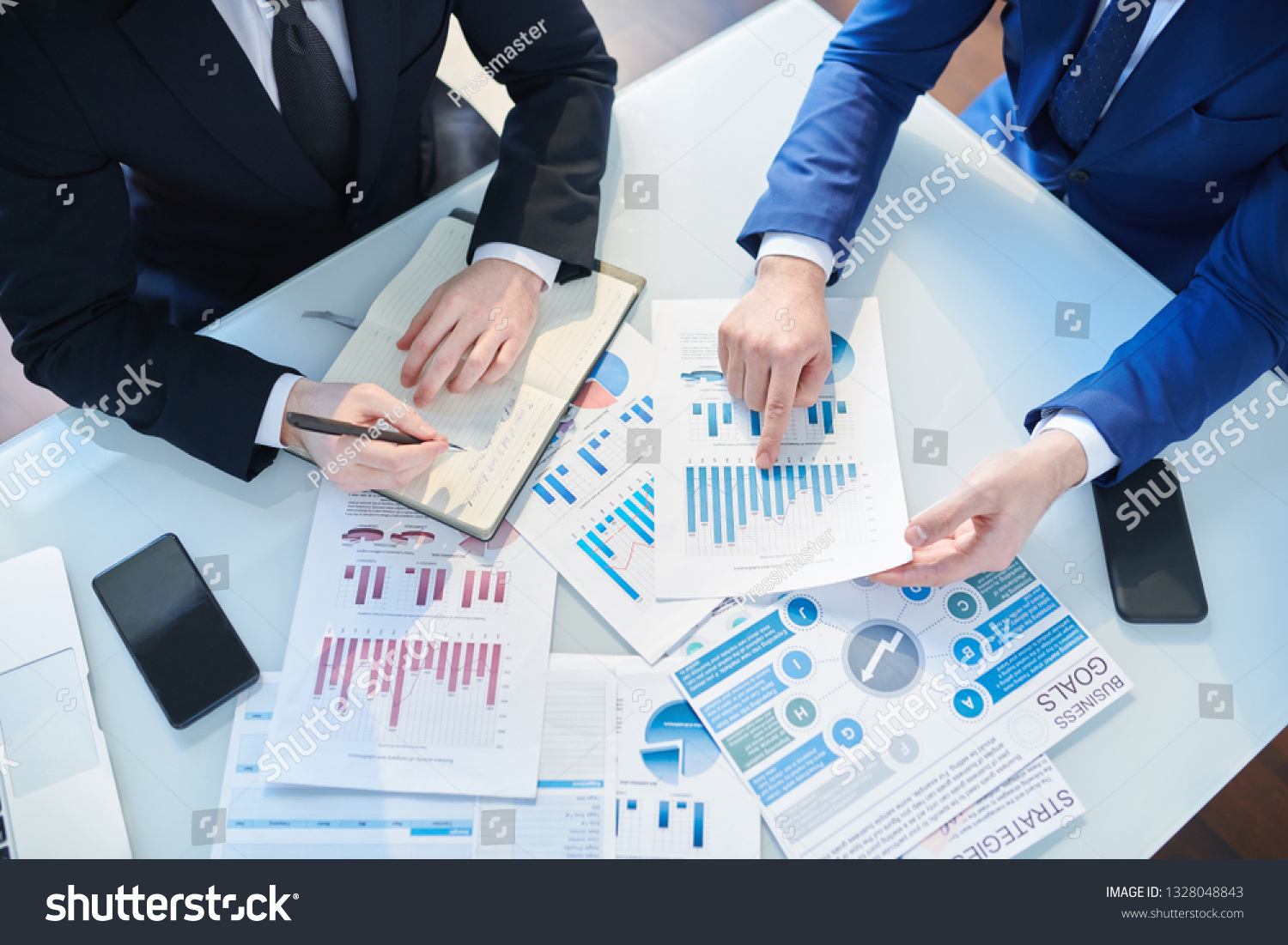 Overview of two businessmen discussing financial papers by desk while organizing work and analyzing statistics #1328048843