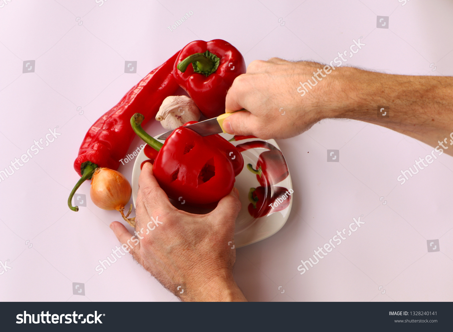 Close-up . Cook hands cutting up a salad of pepper, onion and garlic on a white background. #1328240141