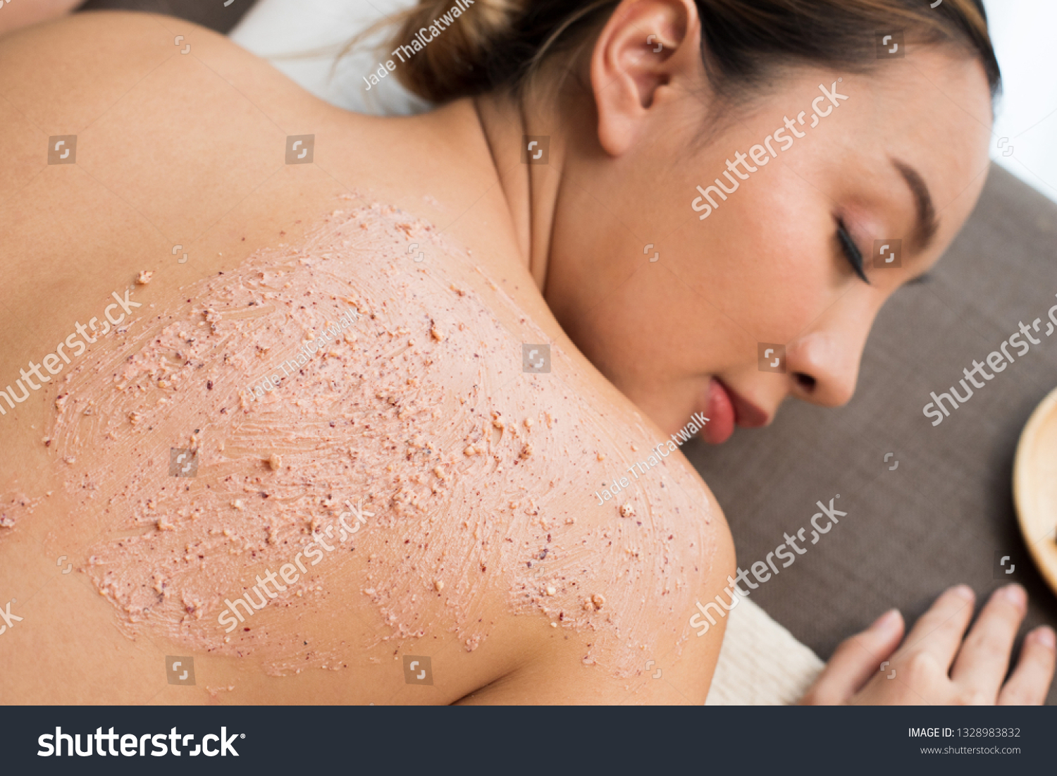 Professional Therapist scrub with light gentle green herbal Beauty Treatment on Mix Race Caucasian Asian woman skin back in the Health Spa, for smooth clean refresh new skin by scrubing old one #1328983832