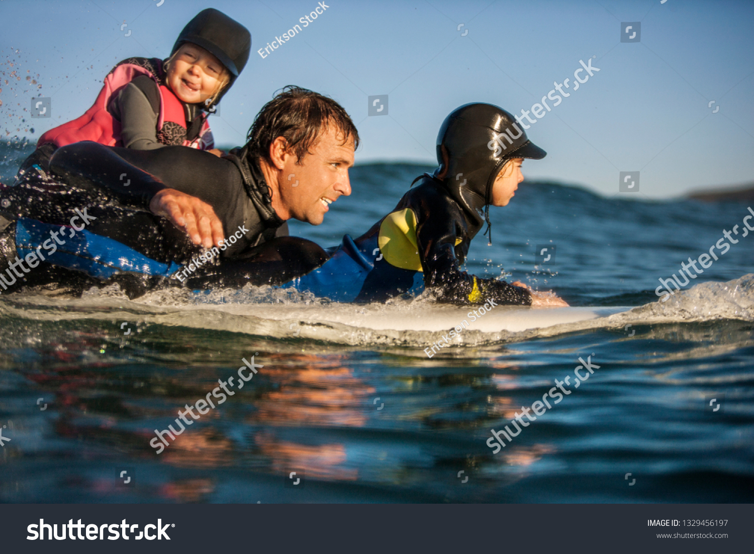 Middle aged man surfing with his two young daughters. #1329456197