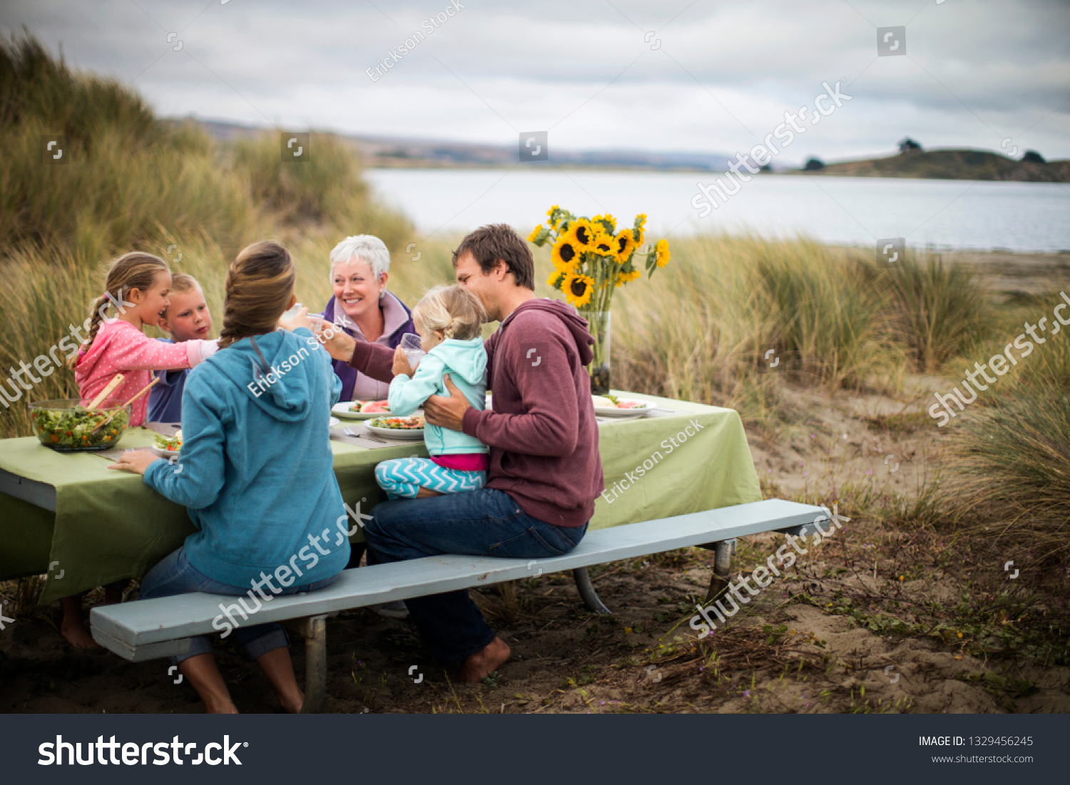 Happy multi-generational family enjoy an outdoor lunch at the beach. #1329456245