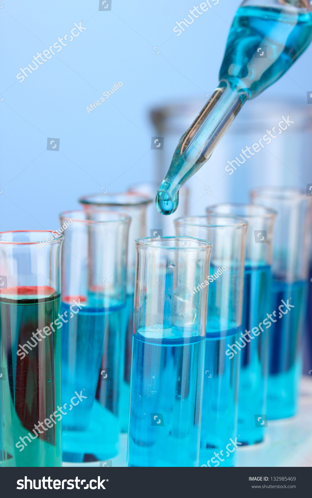 Laboratory pipette with drop of color liquid over glass test tubes, close up #132985469