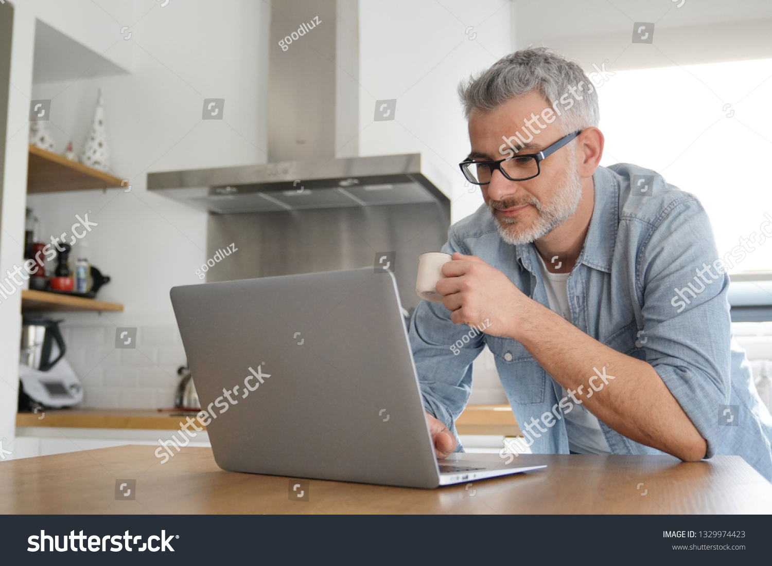 Man with computer at home in modern kitchen #1329974423