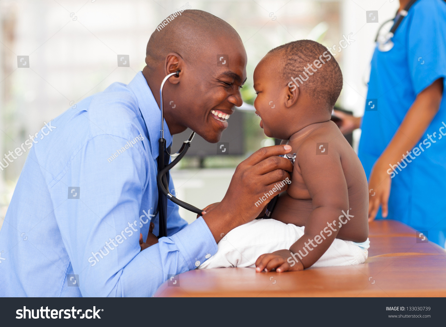 happy african male doctor examining baby boy with female nurse on background #133030739