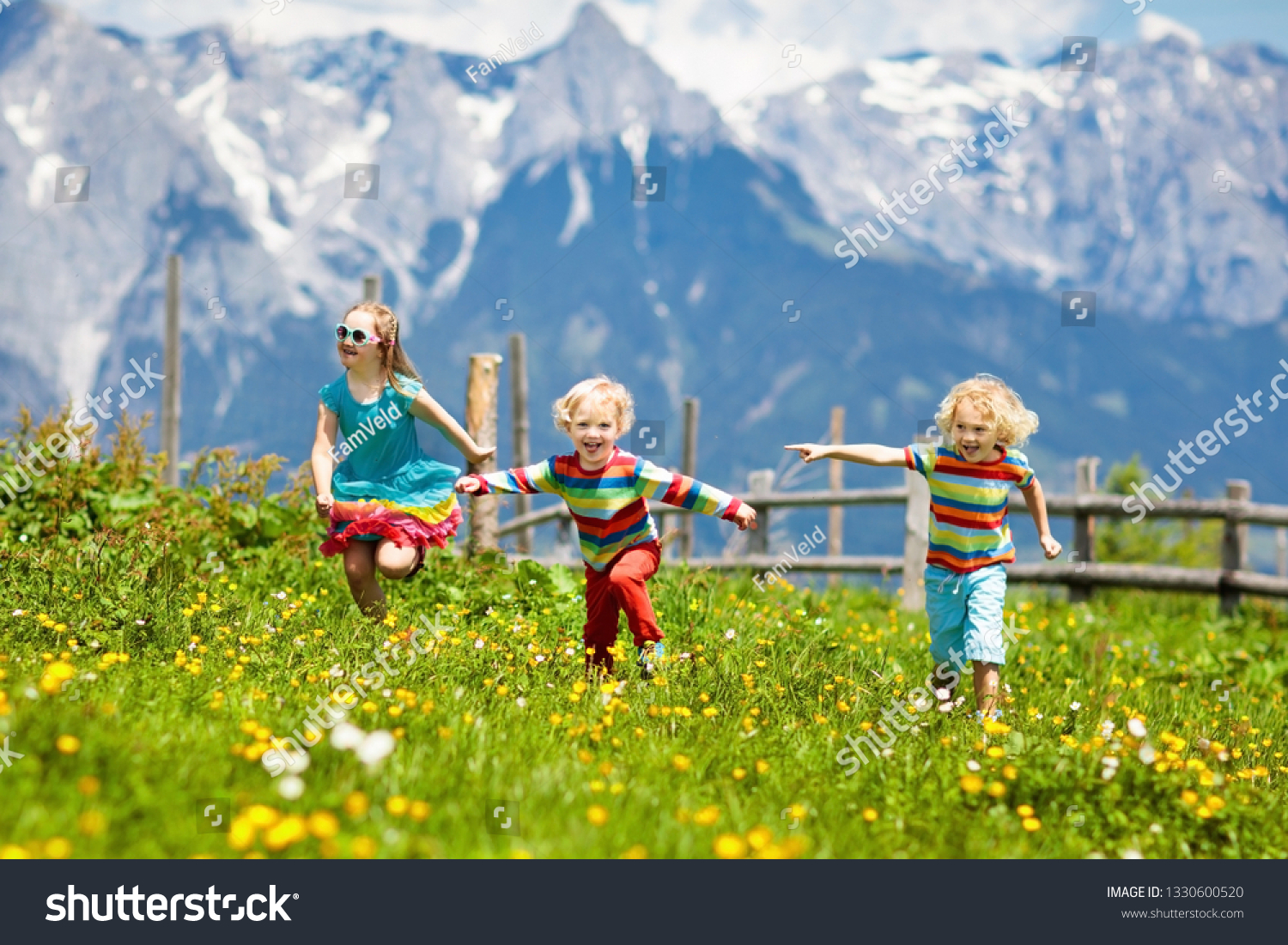Children hiking in Alps mountains. Kids run at snow covered mountain in Austria. Spring family vacation. Little boy and girl on hike trail in blooming alpine meadow. Outdoor fun and healthy activity

 #1330600520