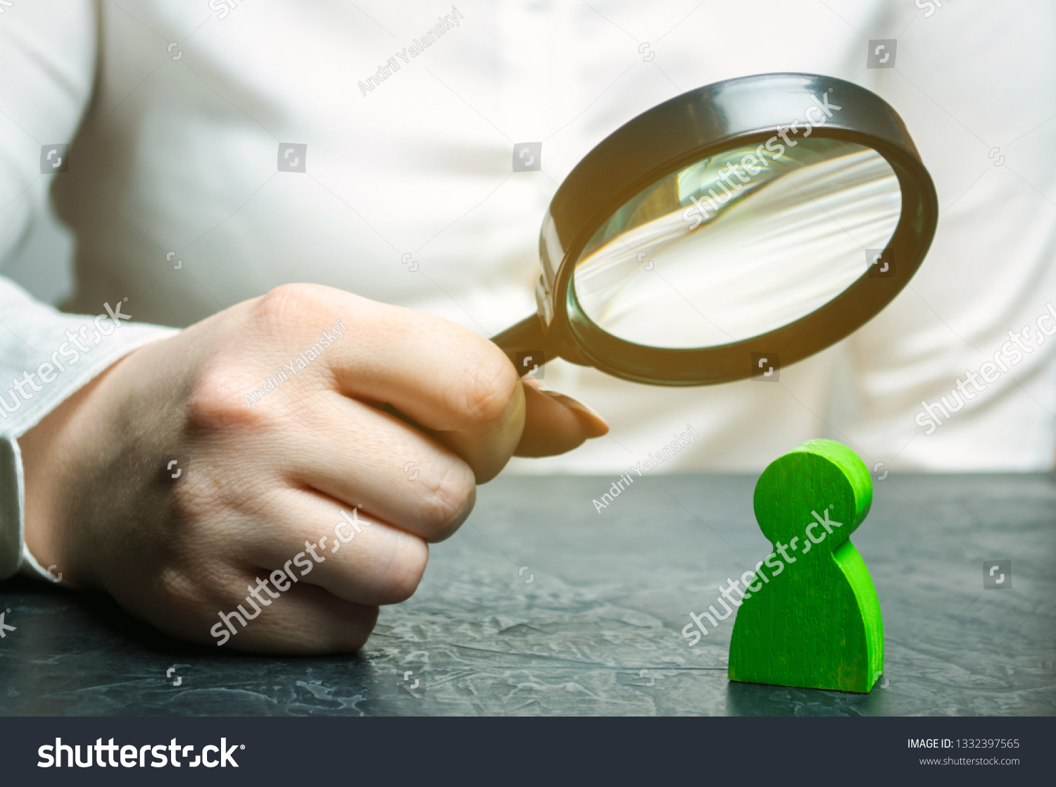 Businesswoman is holding a magnifying glass over a green man figure. Search for a talented employee. Identifying strengths in the company. Disclosure skills. Employee characteristics #1332397565
