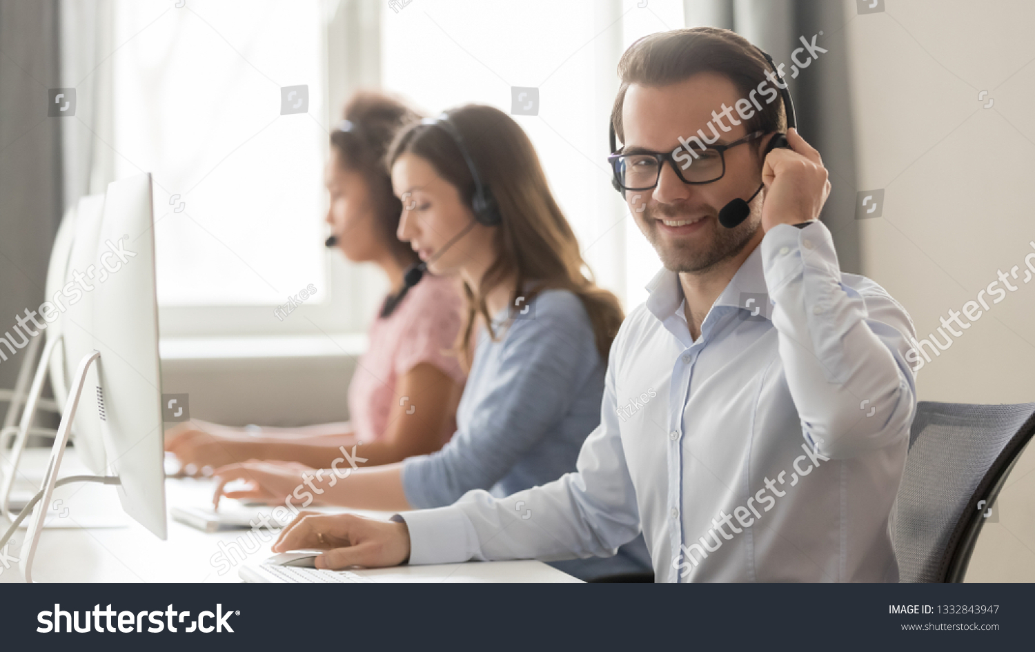 Smiling male call center operator in wireless headset with microphone looking at camera at workplace, businessman agent telemarketer work in customer service helpline support team office, portrait #1332843947