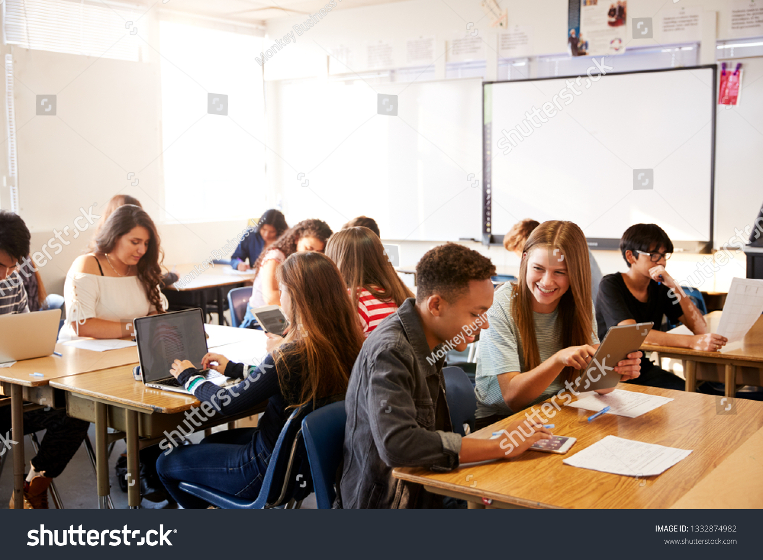 Wide Angle View Of High School Students Sitting At Desks In Classroom Using Laptops #1332874982