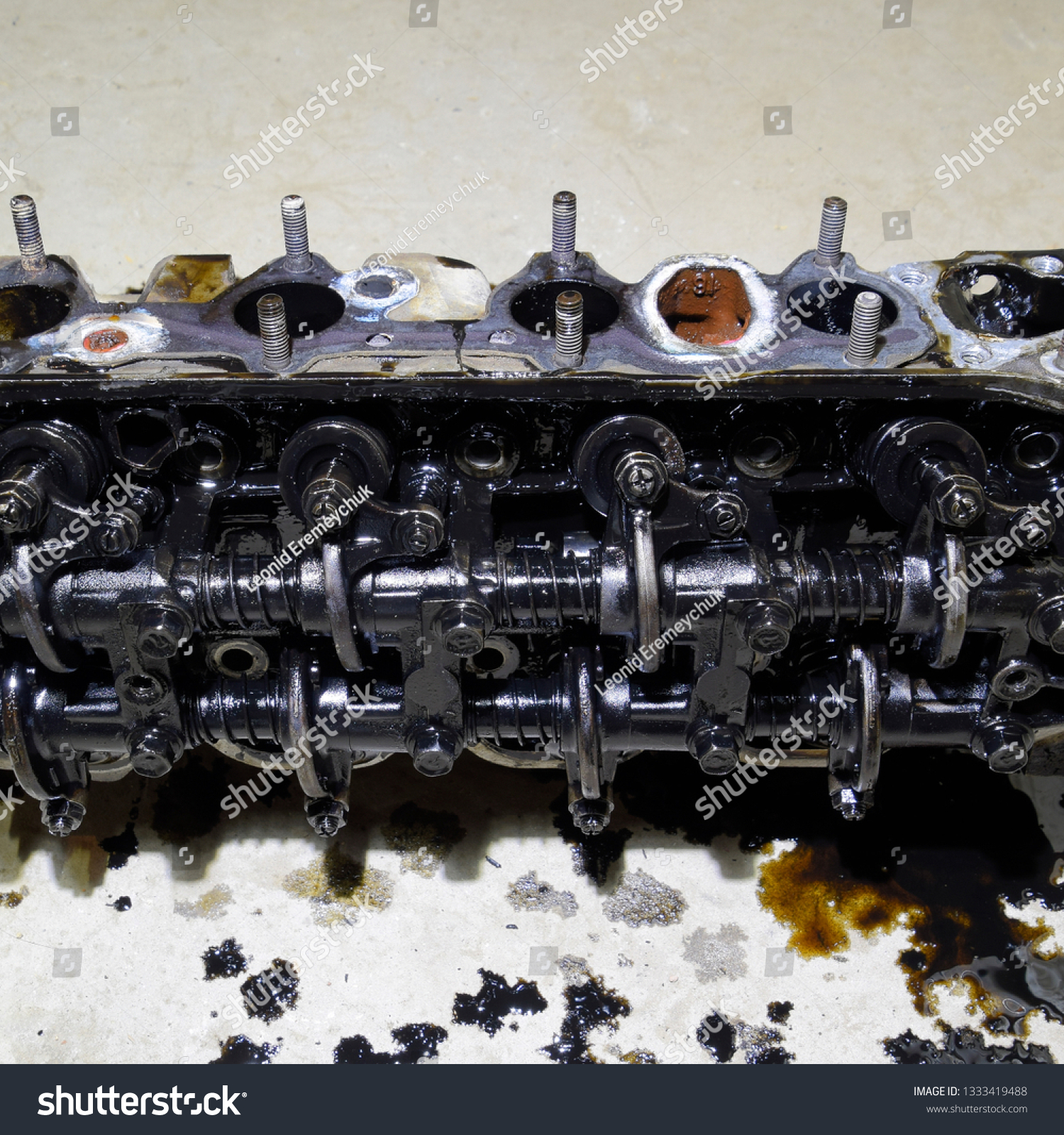 The head of the block of cylinders. The head of the block of cylinders removed from the engine for repair. Parts in engine oil. Car engine repair in the service. #1333419488