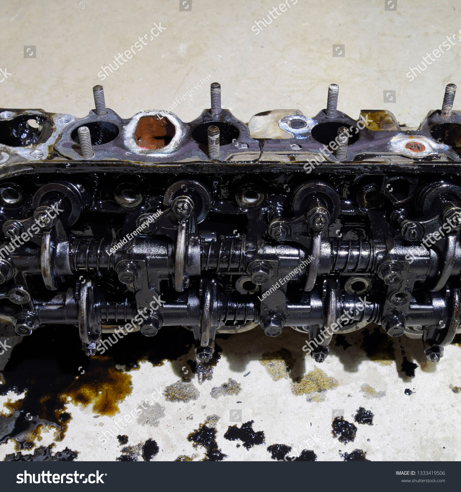 The head of the block of cylinders. The head of the block of cylinders removed from the engine for repair. Parts in engine oil. Car engine repair in the service. #1333419506