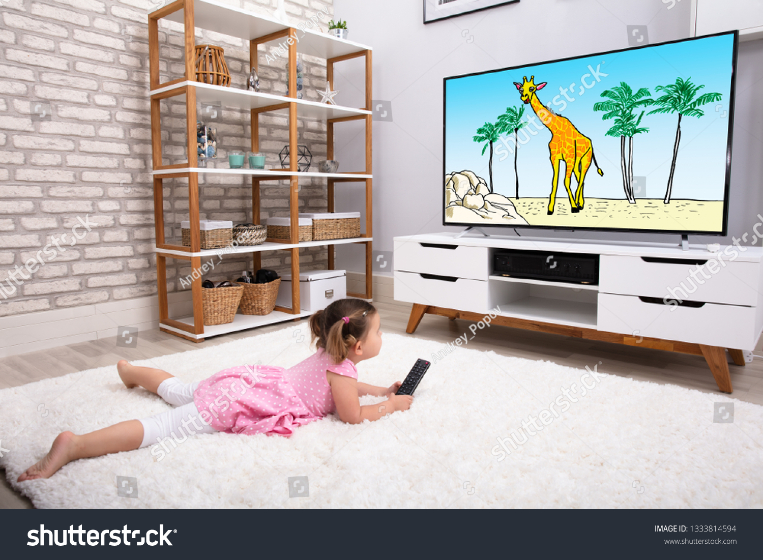 Rear View Of Innocent Girl Lying On Carpet Watching Cartoon On Television #1333814594