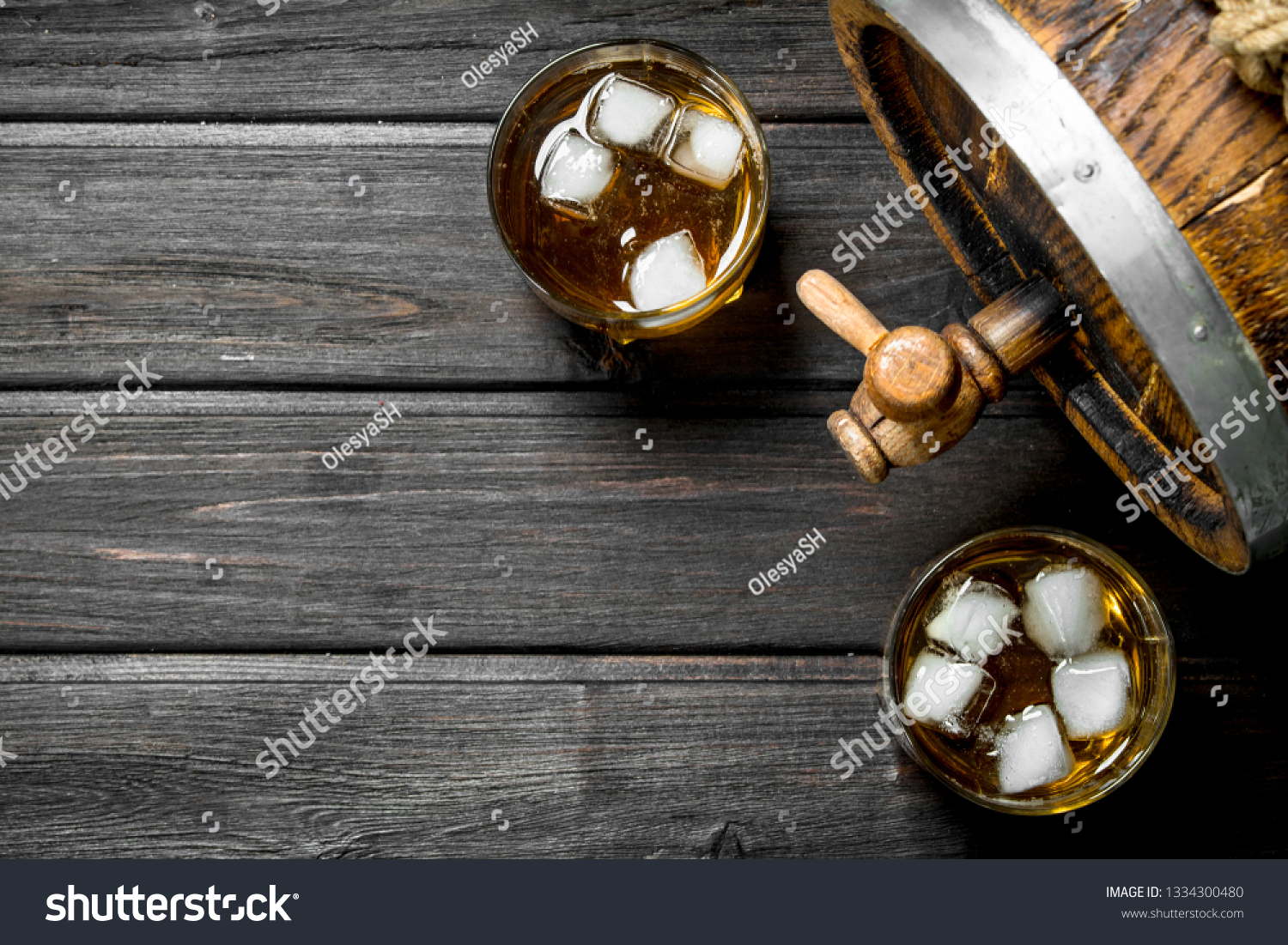 Whiskey in glasses with ice and a wooden barrel. On wooden background #1334300480
