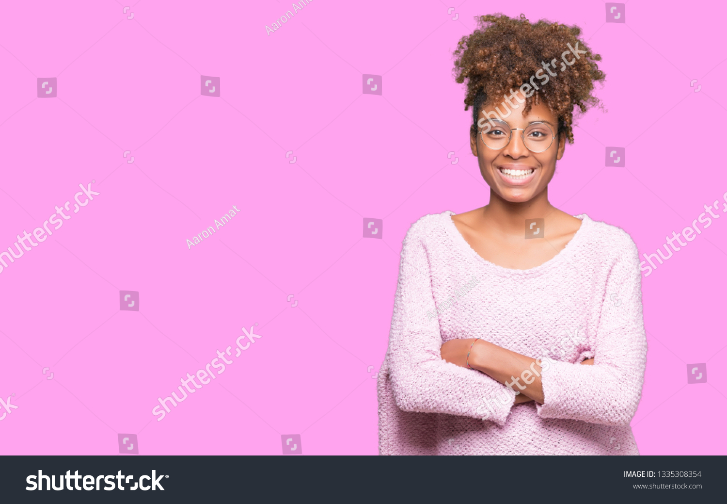 Beautiful young african american woman wearing glasses over isolated background happy face smiling with crossed arms looking at the camera. Positive person. #1335308354