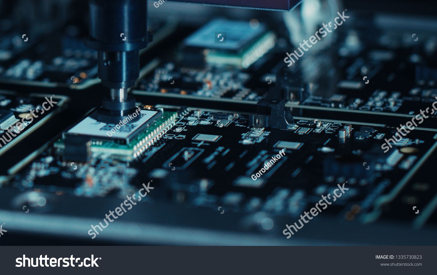Close-up Macro Shot of Electronic Factory Machine at Work: Printed Circuit Board Being Assembled with Automated Robotic Arm, Place Technology Mounts Microchips to the Motherboard #1335730823