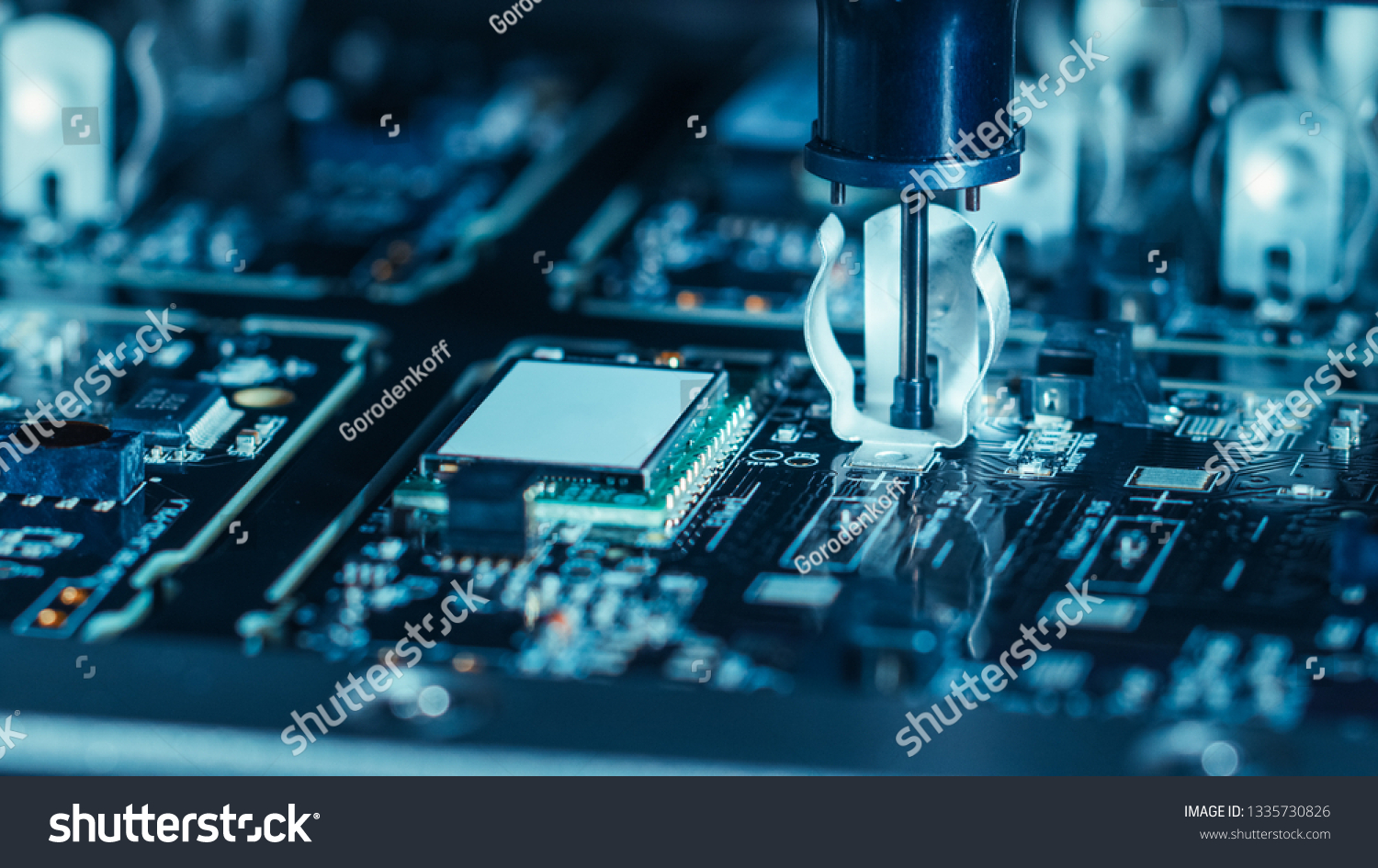 Close-up Macro Shot of Electronic Factory Machine at Work: Printed Circuit Board Being Assembled with Automated Robotic Arm, Place Technology Mounts Microchips to the Motherboard #1335730826