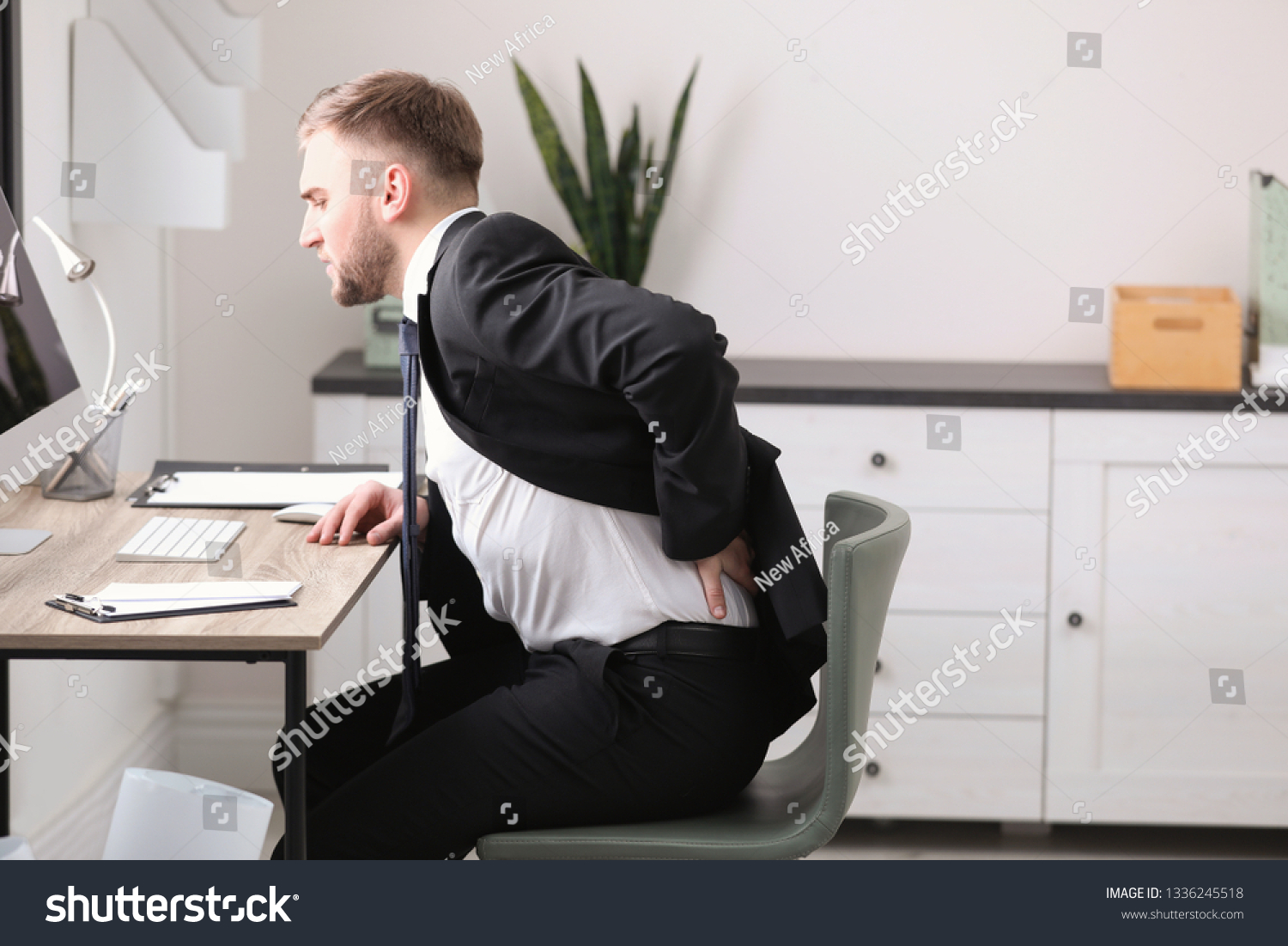 Businessman suffering from back pain at workplace #1336245518