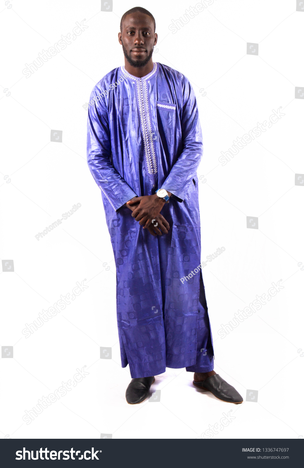 Young and handsome. Handsome young African senegalese man in smart casual jacket holding hands in pockets and traditional smiling while standing against white background #1336747697