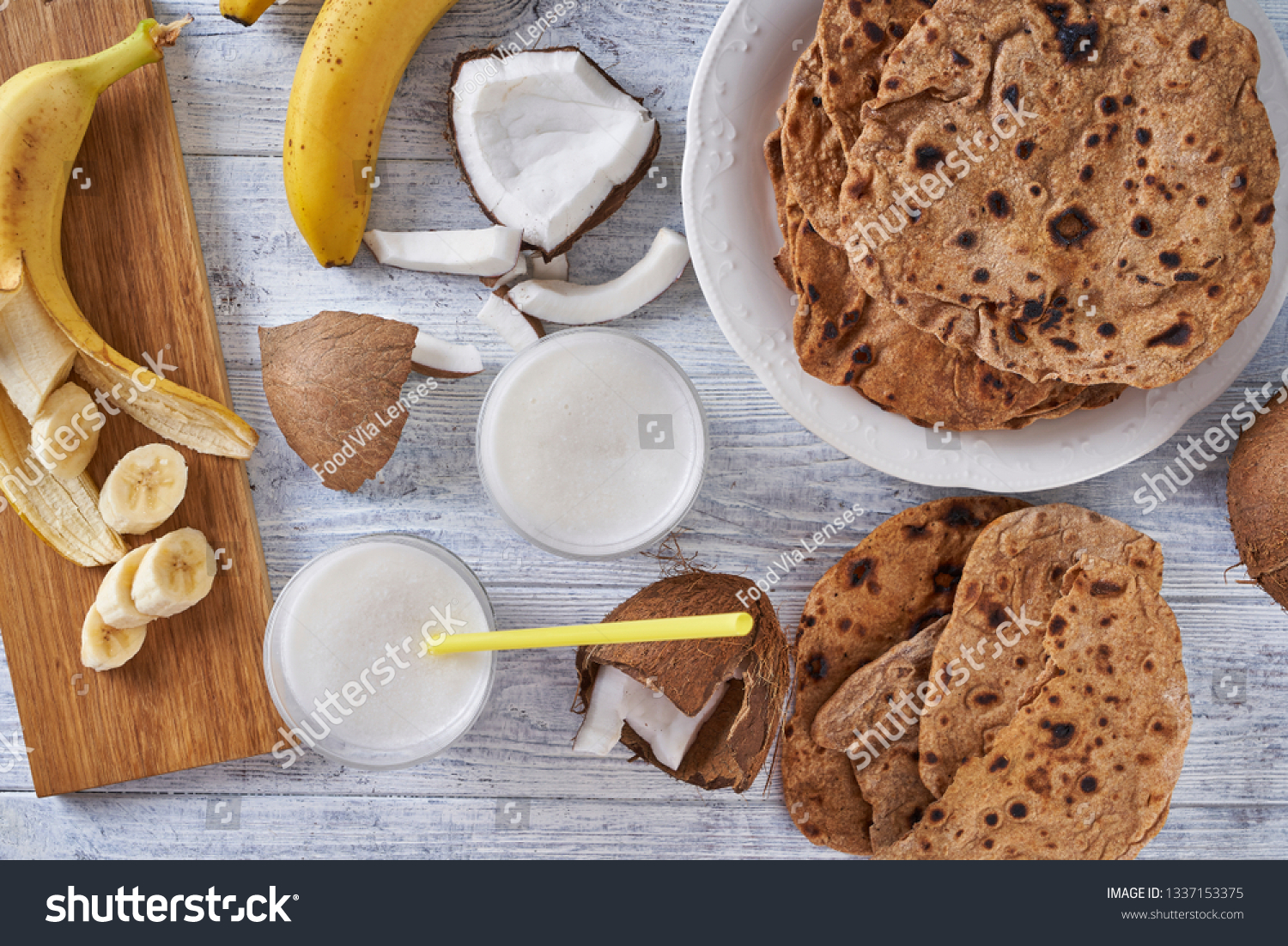 Close up on whole wheat asian flatbread roti with lactose free coconut milk and ripe banana on a cutting board, top view, flat lay, horizontal #1337153375