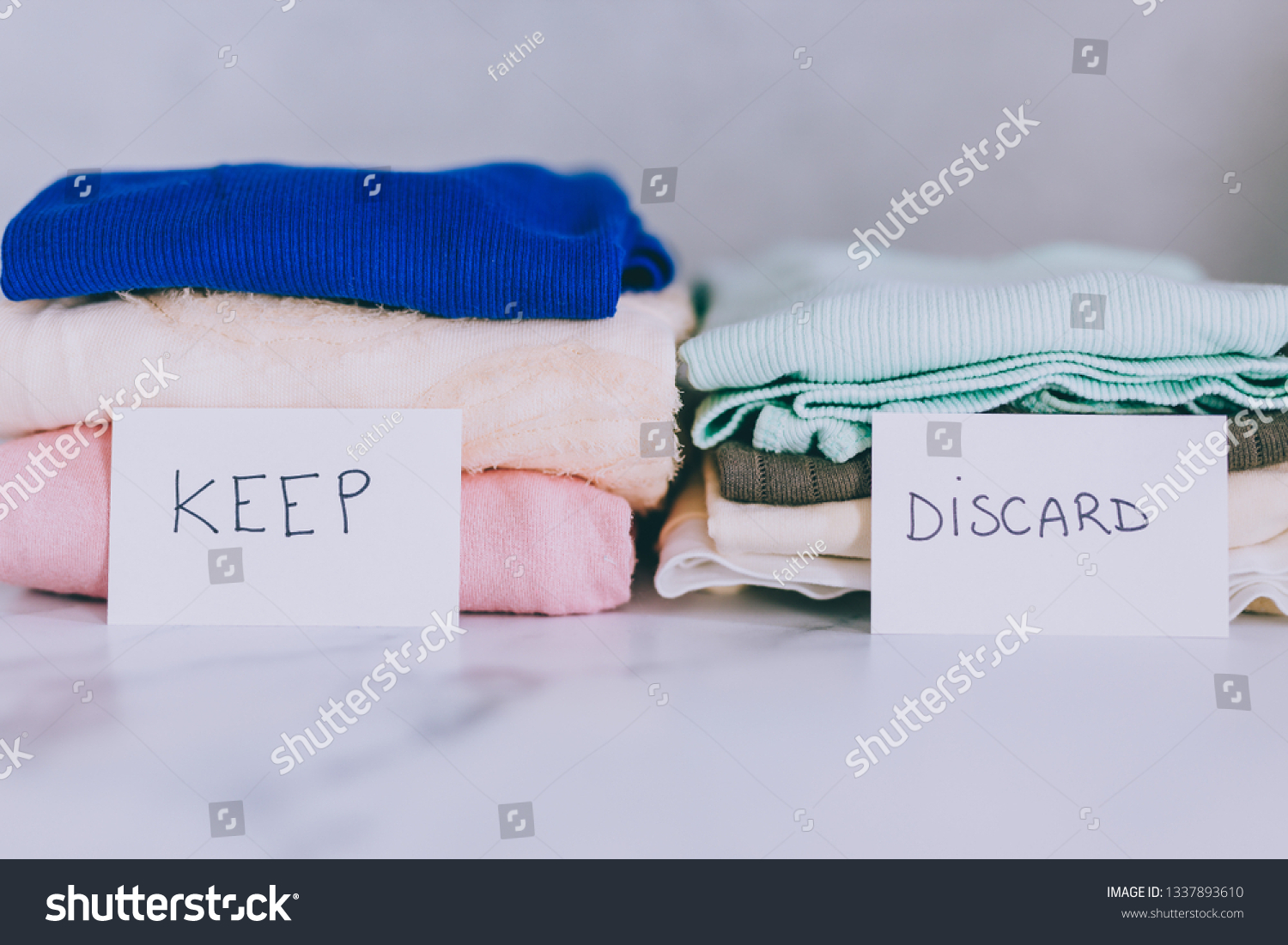 decluttering and tidying up concept: piles of tshirts and clothes being sorted into Keep Discard and Donate categories #1337893610