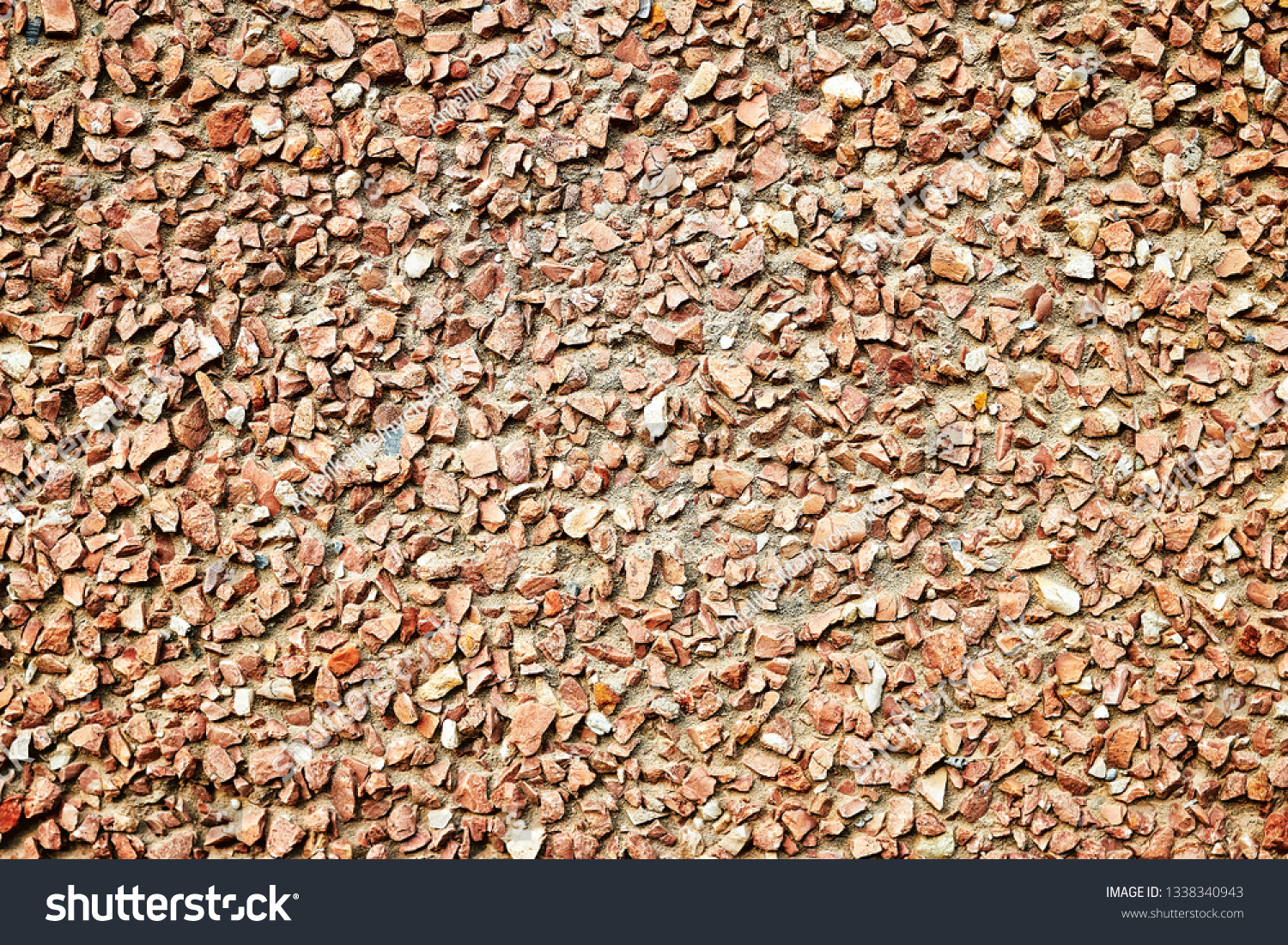 The surface is made of small reddish reddish bright gravel for the background, wallpaper, design. #1338340943