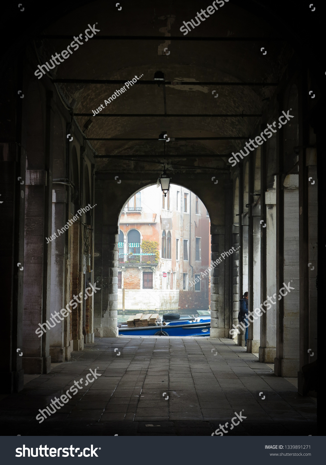 A boat on a canal seen through an archway in Venice, Italy.  Venice is famous for its canals, which are used instead of roads for transport throughout the city.   #1339891271