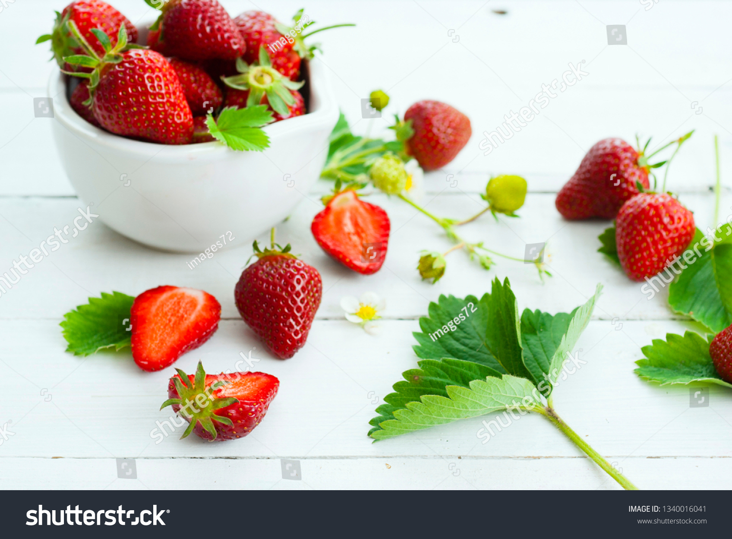 fresh ripe and under ripe strawberry fruits, flowers, leaves on white wood table background #1340016041
