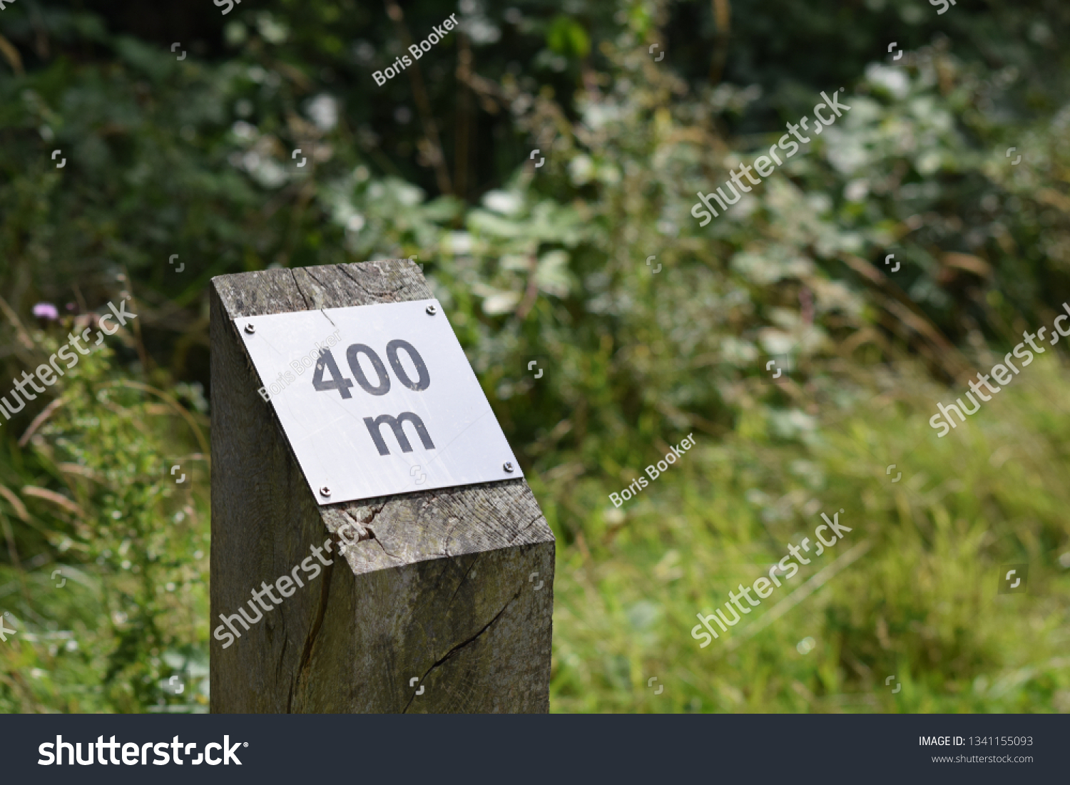 400 meter sign on wooden post with grass and trees in background #1341155093