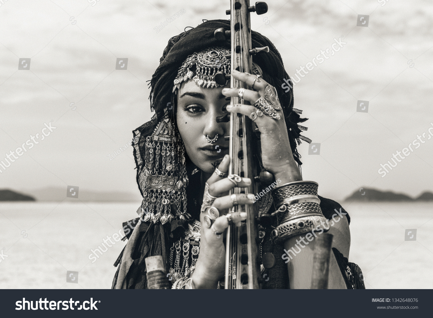 Beautiful young stylish tribal woman in oriental costume playing sitar outdoors. Close up #1342648076