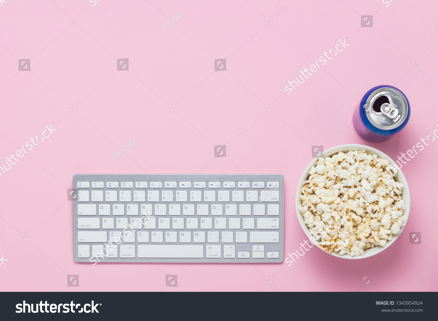 Keyboard, can with a drink and a bowl of popcorn on a pink background. The concept of watching movies, TV shows and shows online. Flat lay, top view. #1343954924