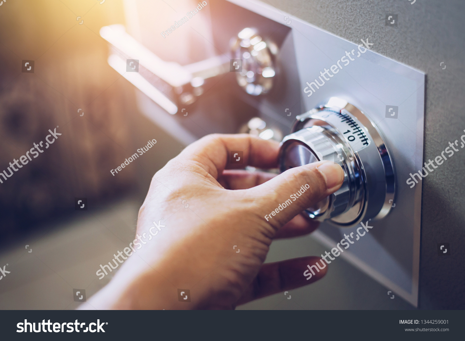 Close up of a man hand hold and tuning on a combinations safe dial lock #1344259001
