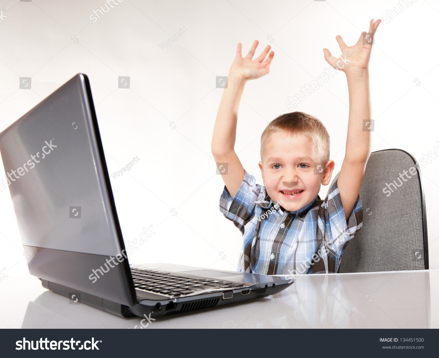 Triumphing child boy with a laptop notebook computer isolated on white background. Computer addiction. #134451500