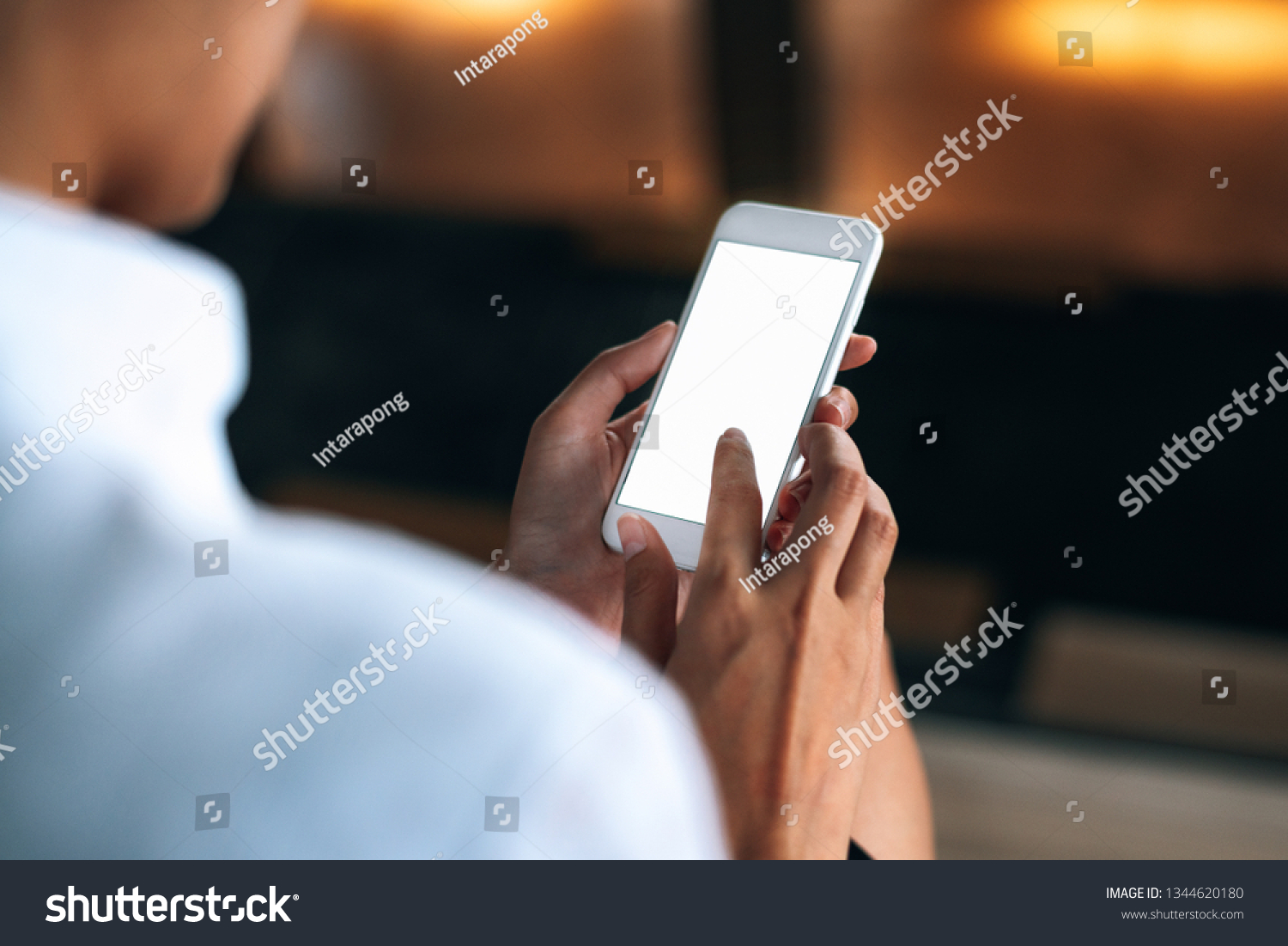 Woman using a smartphone read and text messages with blank space screen display from behind view- woman office worker- digital and communication concept #1344620180