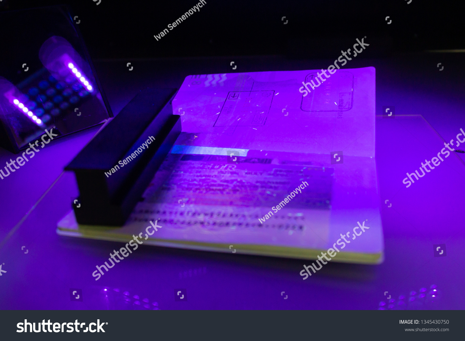 Process of the passport visa checking, close-up. The study of protective elements of the document in ultraviolet light. High security printing for for visa stickers. Passport protection against fraud #1345430750