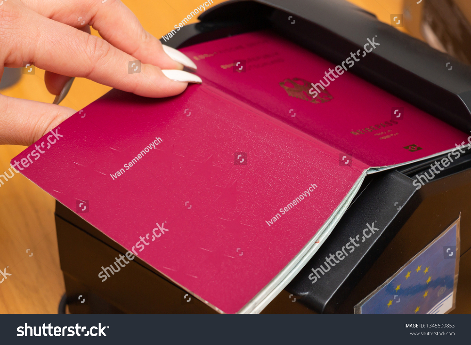 The process of scanning a German biometric passport to register the fact of crossing the state border. Female hand puts a passport to the scanning device. Concept of overseas travel, immigration #1345600853