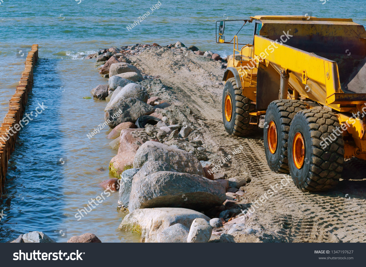 Construction of breakwaters in the sea. Construction equipment and machinery on the seashore. #1347197627