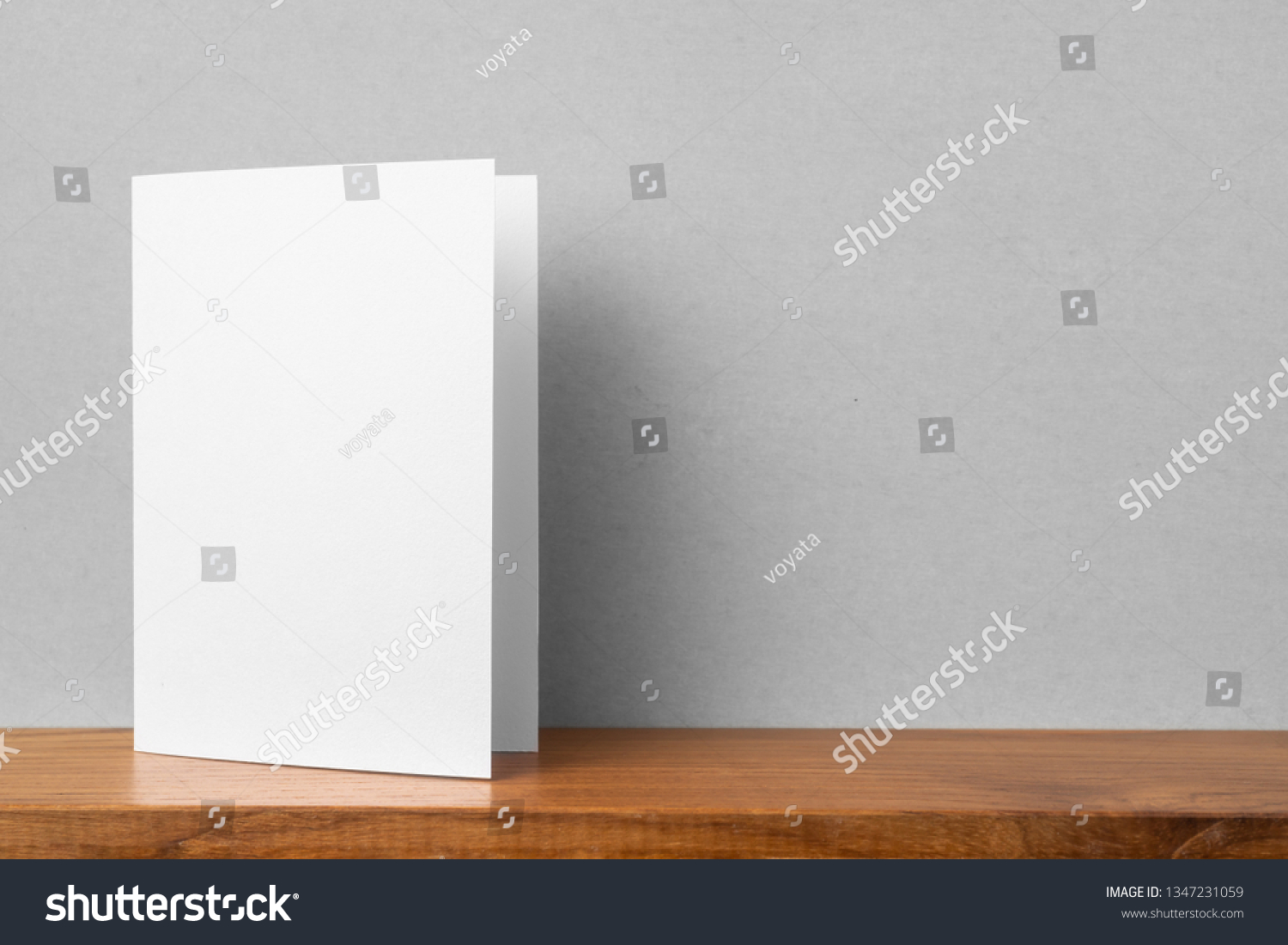 Design concept - front view of greeting card on bookshelf and grey wall for mockup, not 3D render #1347231059
