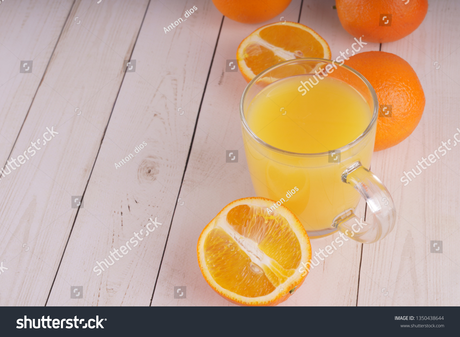 Glass of freshly squeezed orange juice standing on light background with a fresh oranges.  Healthy lifestyle concept. Copy space for text. #1350438644