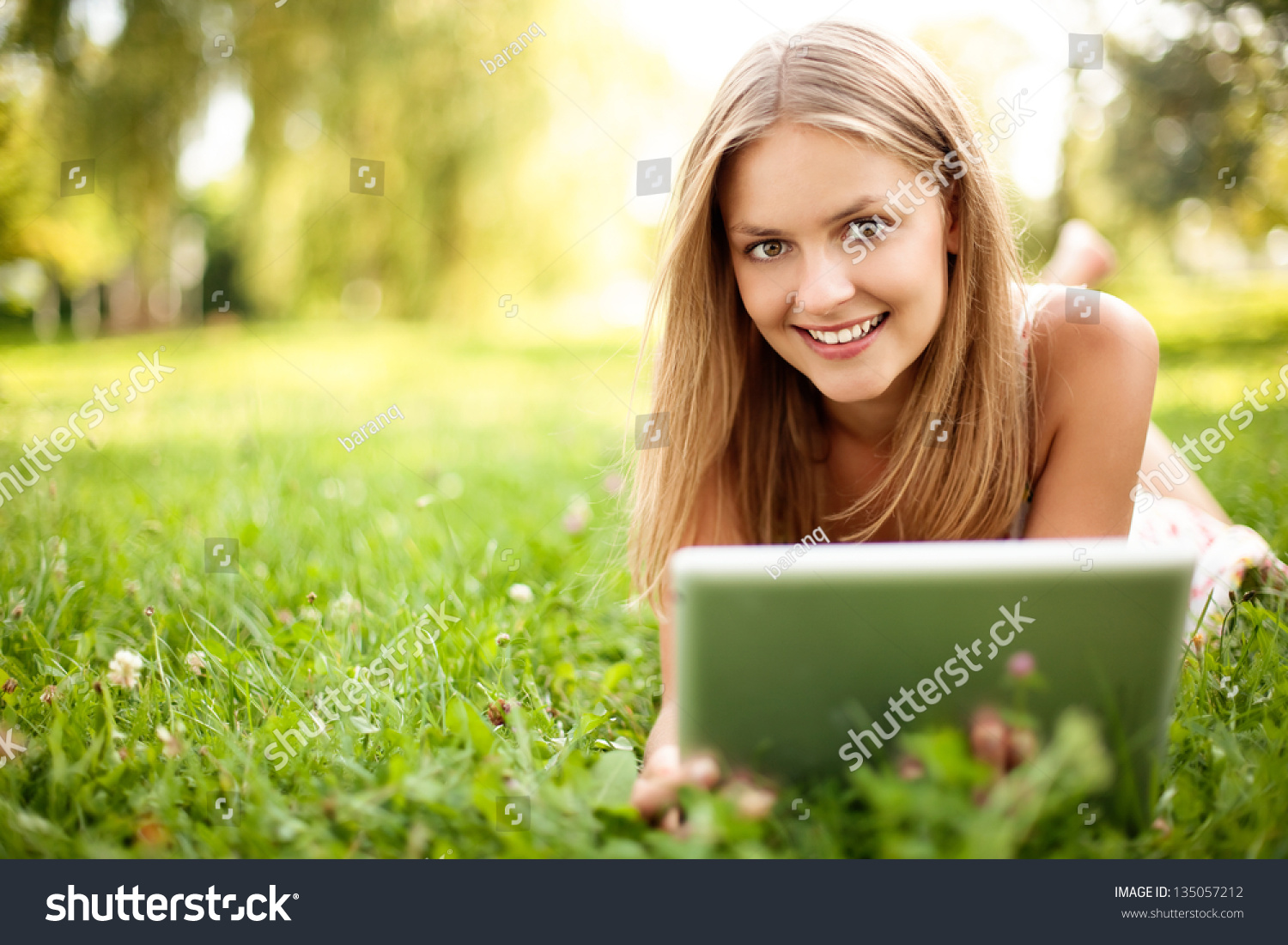 Happy young woman with digital tablet laying on grass #135057212