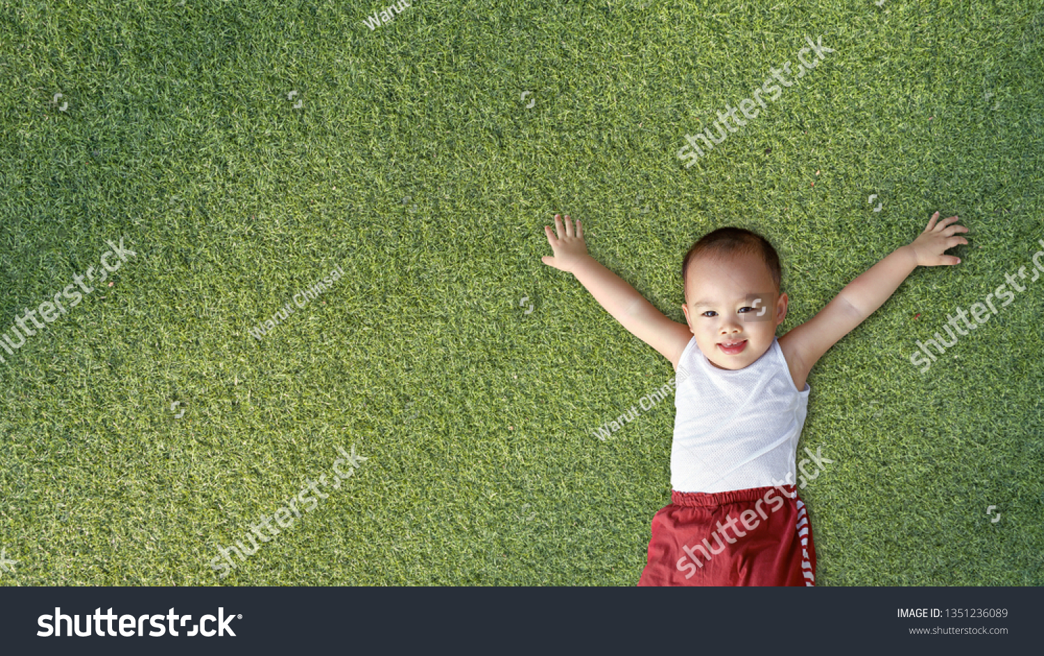 Asian little boy smile and lay on grass  background #1351236089