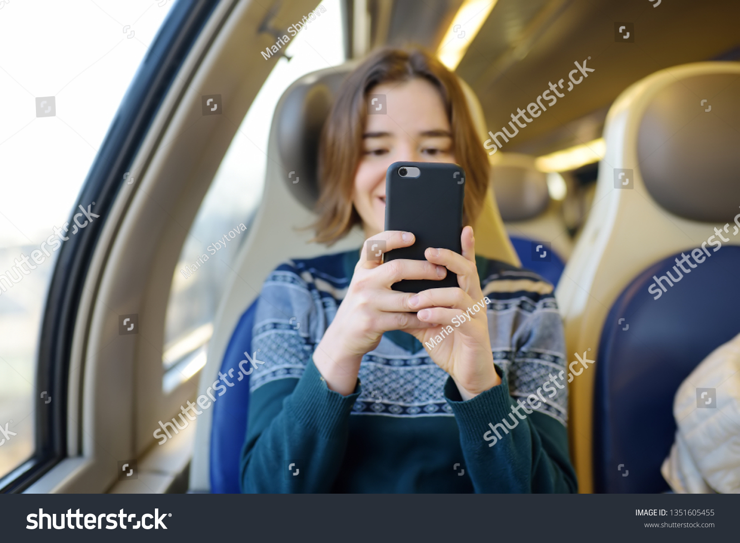 Portrait of a beautiful girl communicating on the phone in a train car. Mobile communication - the joy of communication from everywhere. Modern technologys. #1351605455