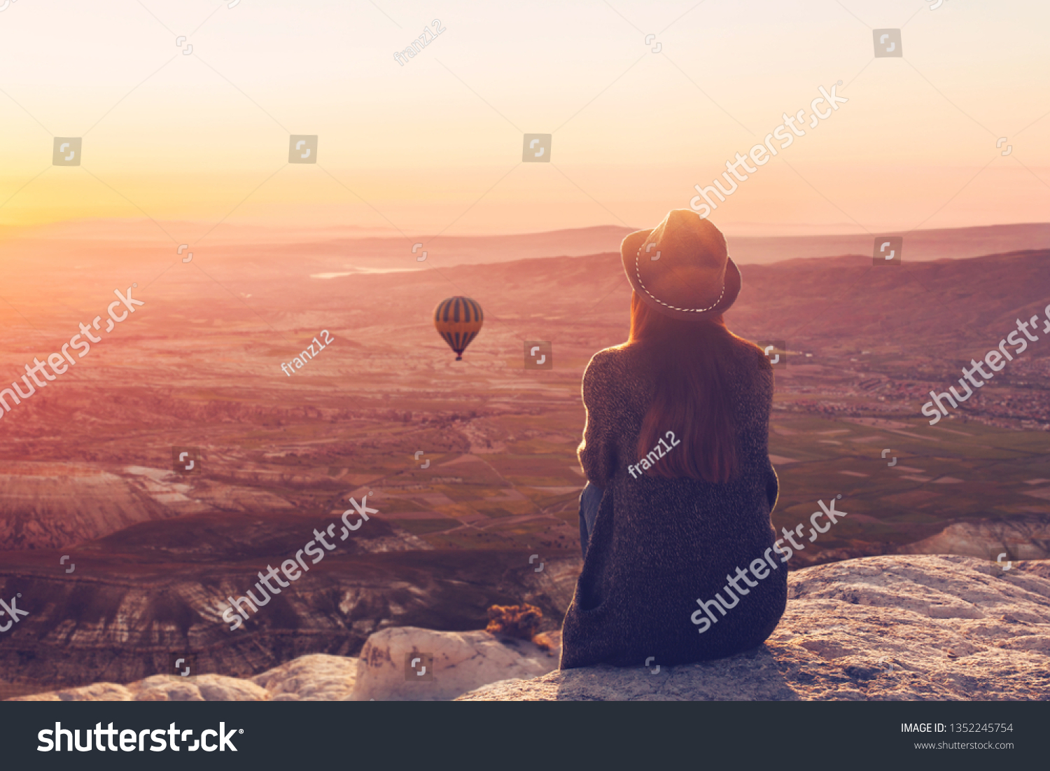 A woman on top of a hill alone admires the tranquil natural landscape and balloon and enjoys silence in Cappadocia in Turkey #1352245754