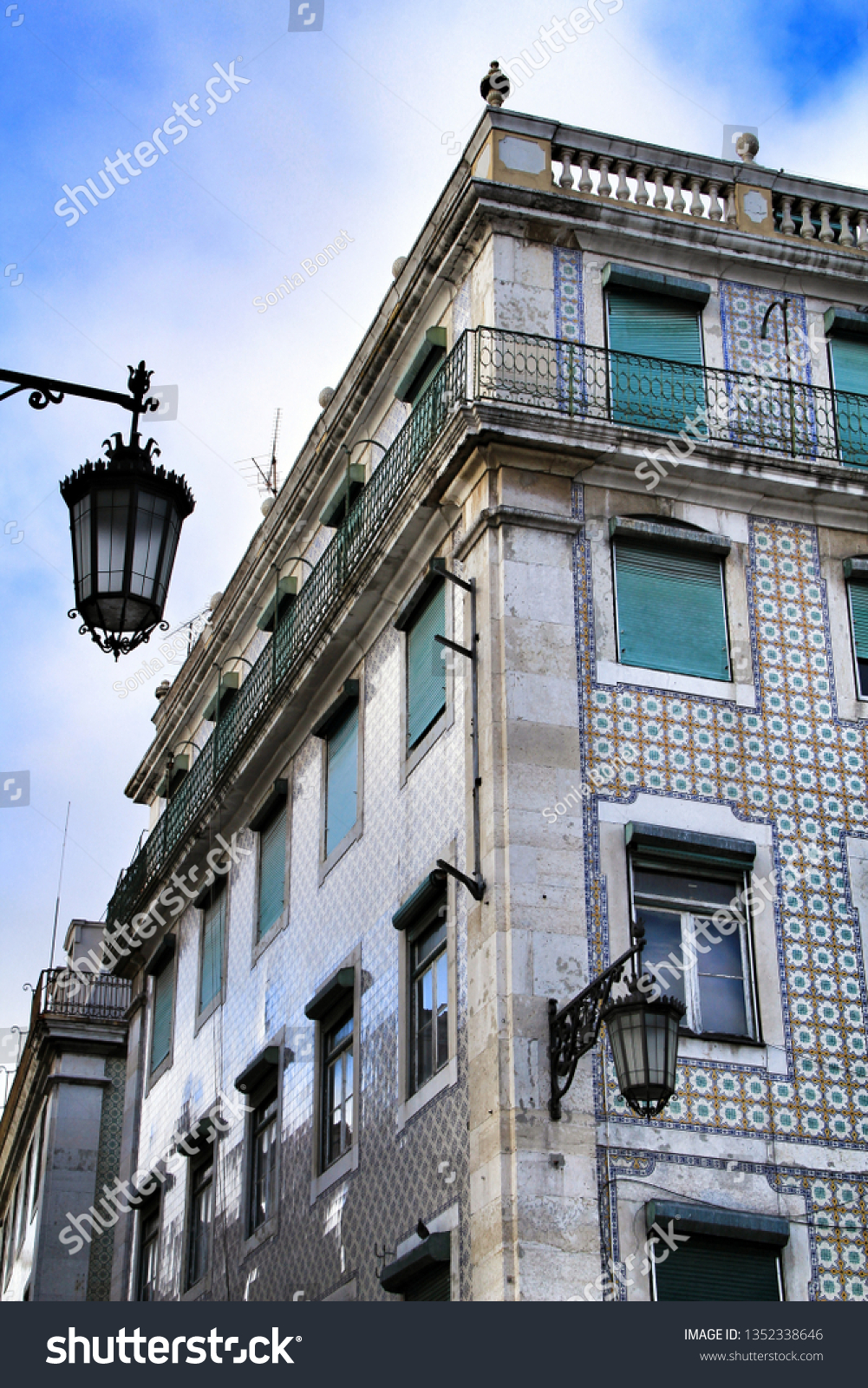 Old colorful and beautiful facades with vintage streetlight in Lisbon streets in Spring. Clothesline in the facade with hanging clothes #1352338646