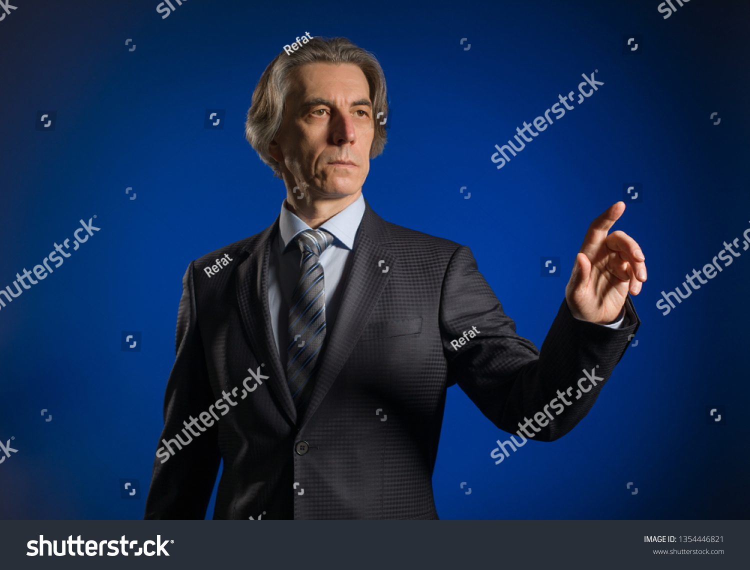 Businessman presses a virtual button on a dark background. #1354446821