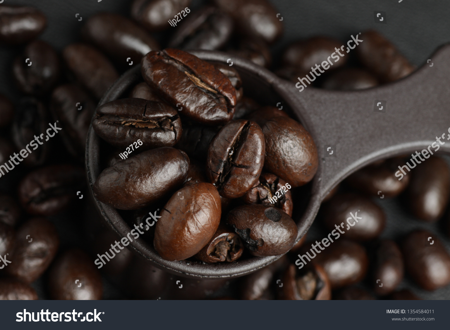 Dark roasted robusta coffee beans on a measuring spoon #1354584011