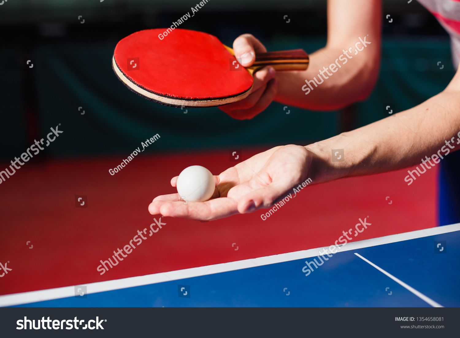 A young man is playing ping pong. He holds a ball and a racket in his hands #1354658081