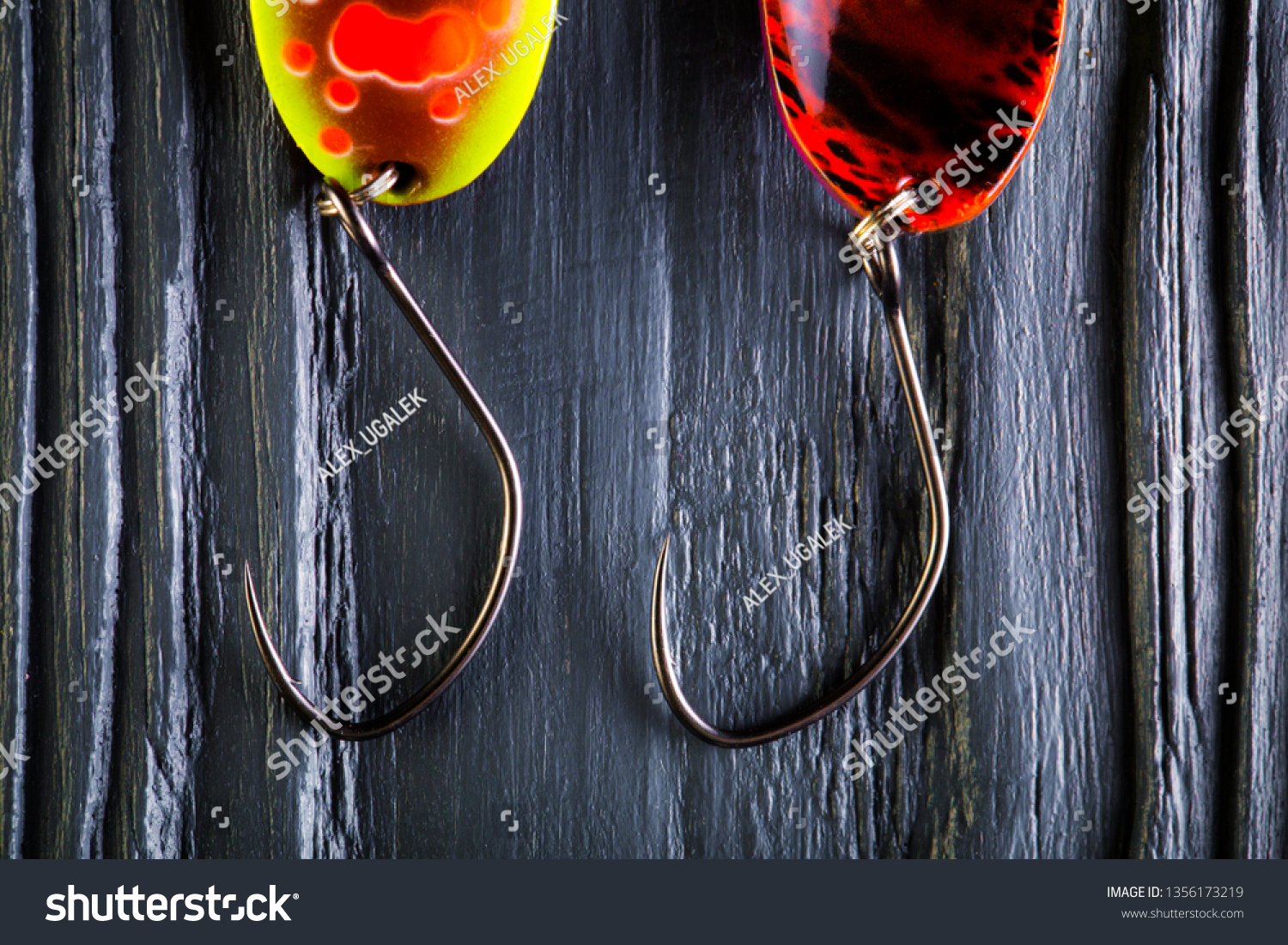 Hooks for trout baits. Spoon baits close-up on black wooden background. Colorful fishing baits. #1356173219