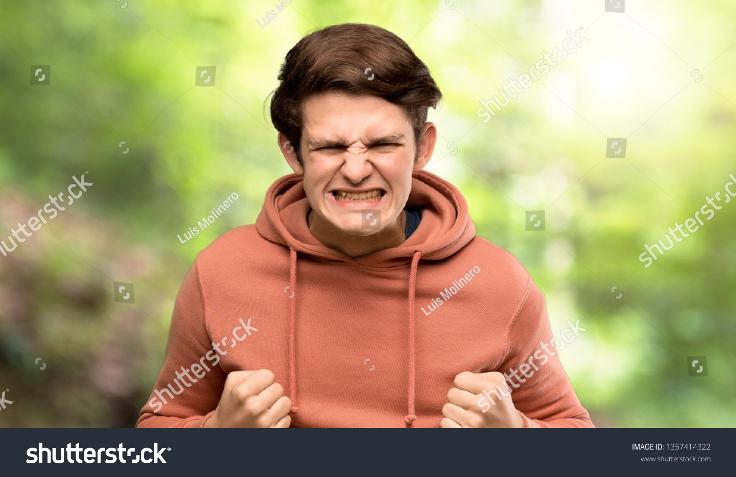 Teenager man with sweatshirt frustrated by a bad situation at outdoors #1357414322