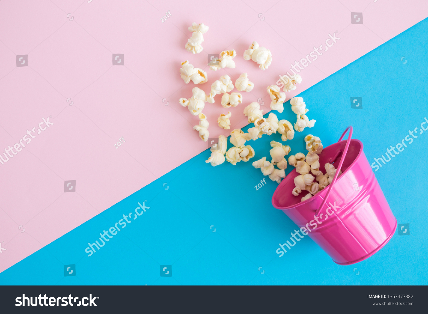 Flat lay of small metal bucket with spilled popcorn on pastel background minimal creative concept. #1357477382